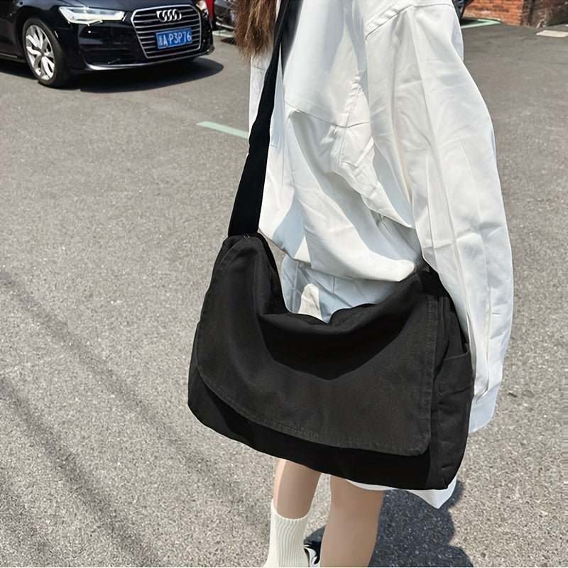 Black canvas messenger shoulder bag worn across the body
