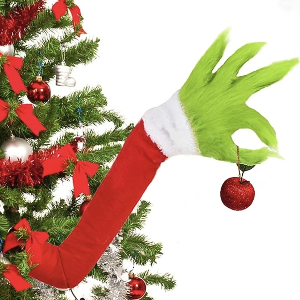 Green furry hand on a red sleeve reaching out of a snowy tree, holding a red glitter bauble between two fingers