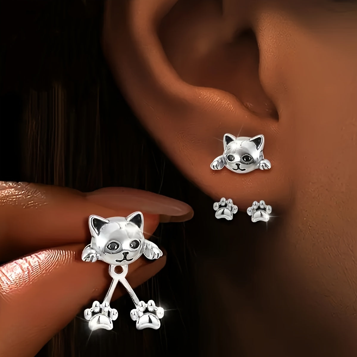Cat ear jacket earring worn on a lobe, with a second one held in the fingers showing the paw drop