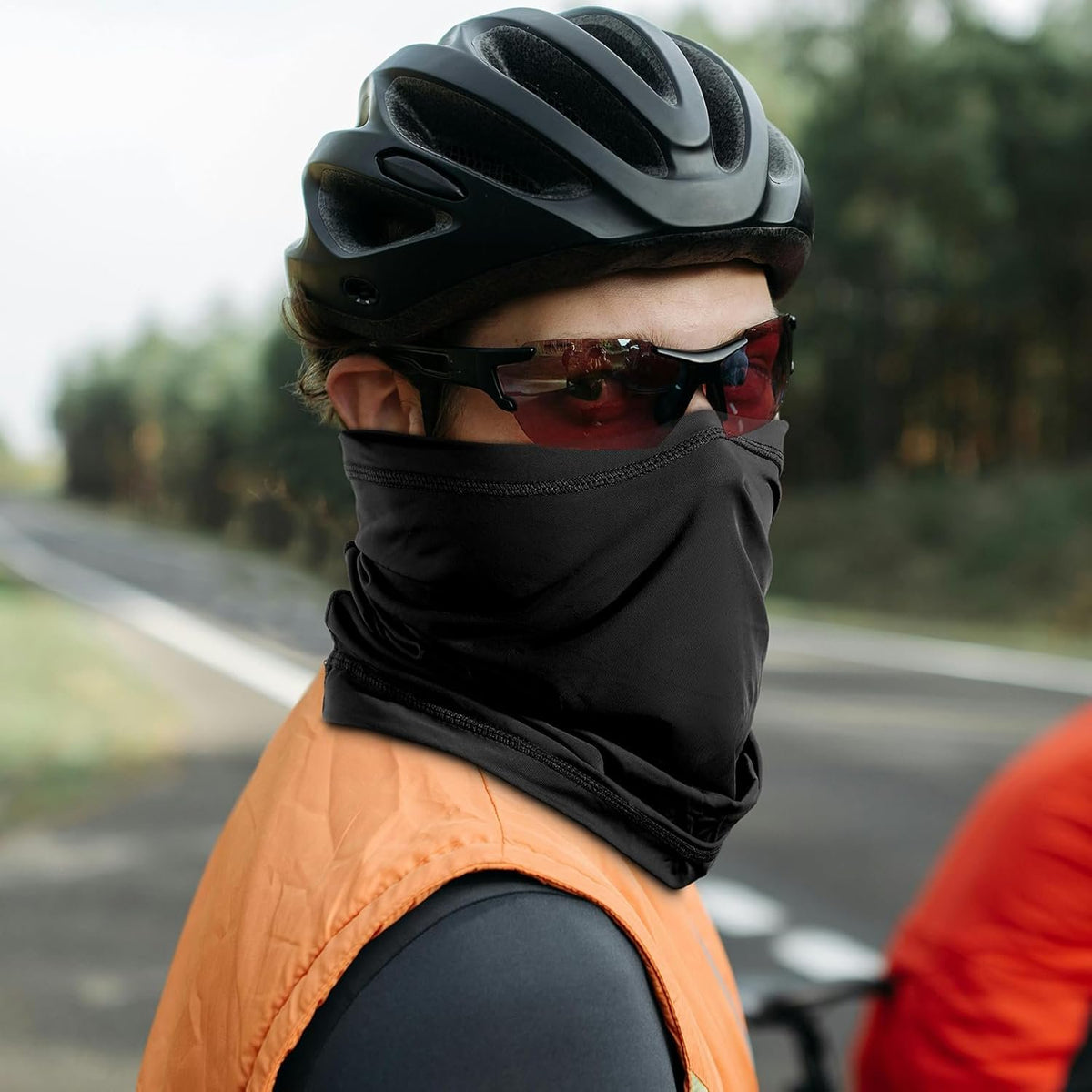 Cyclist on a road wearing the black neck gaiter pulled up over the nose