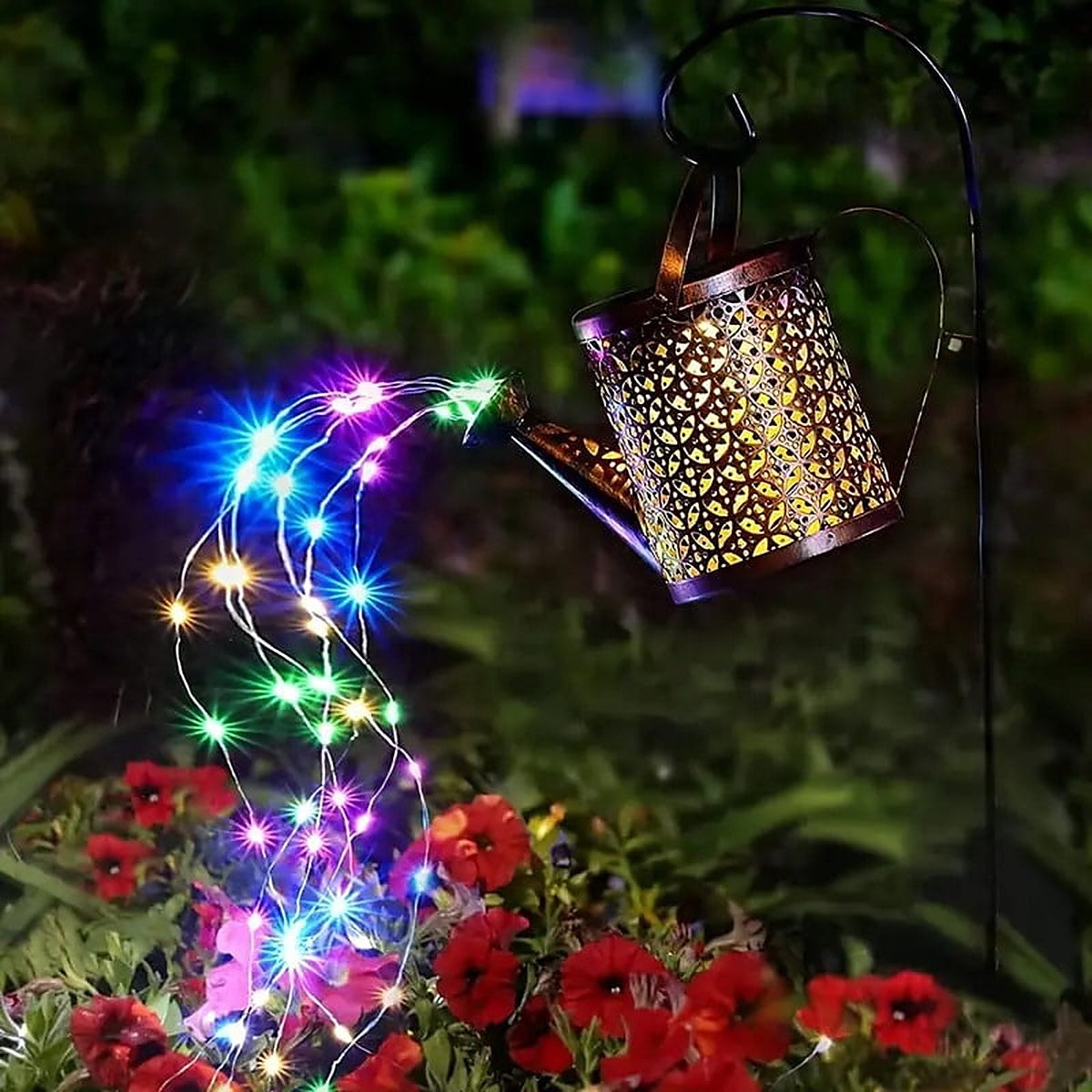 Multicolor strands pouring from the spout over red and white flowers at night