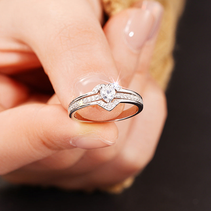 Silver heart ring with sparkling zirconia held between fingers