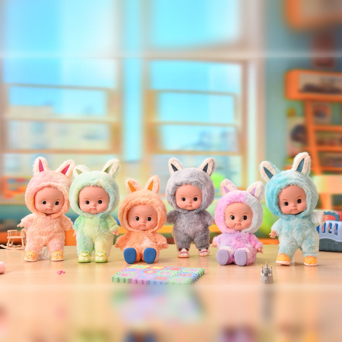 All six eyes open plush onesie doll colors lined up together on a playroom table