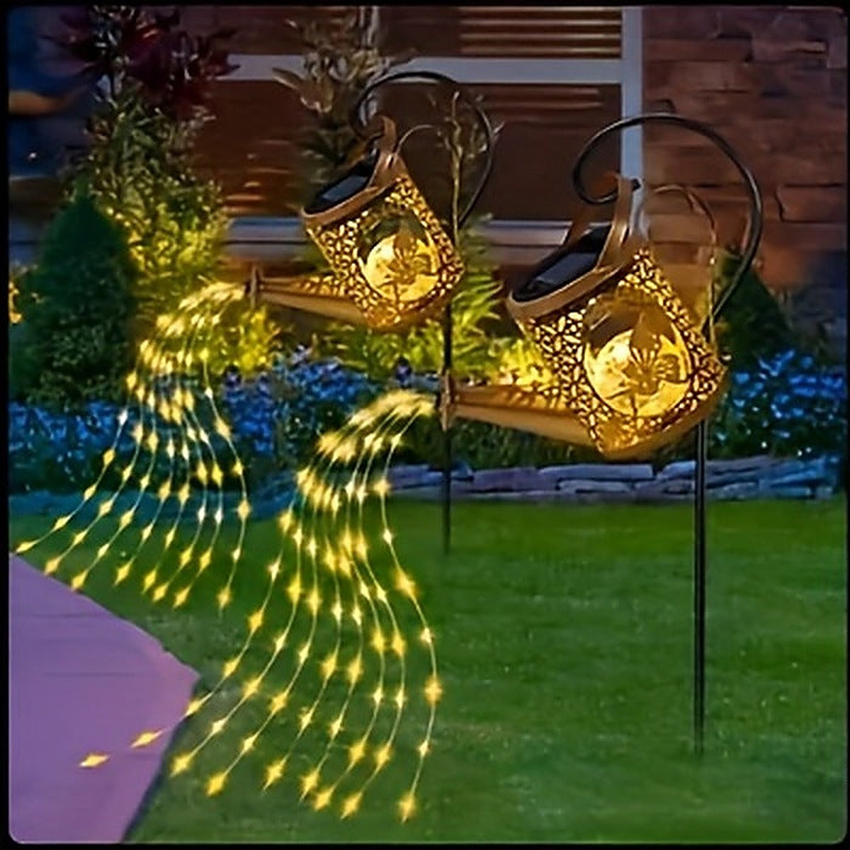 Both watering can lights from the 2-pack staked side by side in a lawn at night
