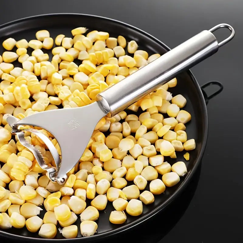 Stainless Steel,Corn Peeler, Planer, Thresher resting on a plate with corn kernels