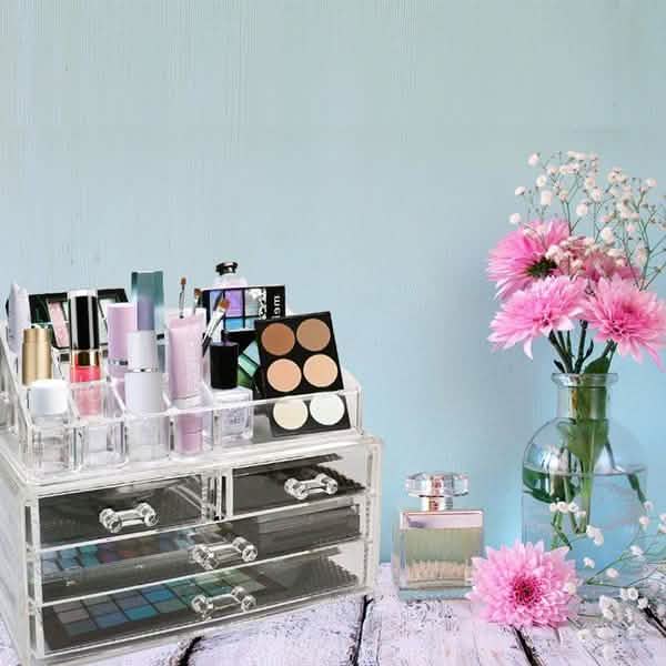 Acrylic Makeup Organizer Cosmetic Jewelry Display Box full of makeup products displayed on top of a table next to a vase with flowers