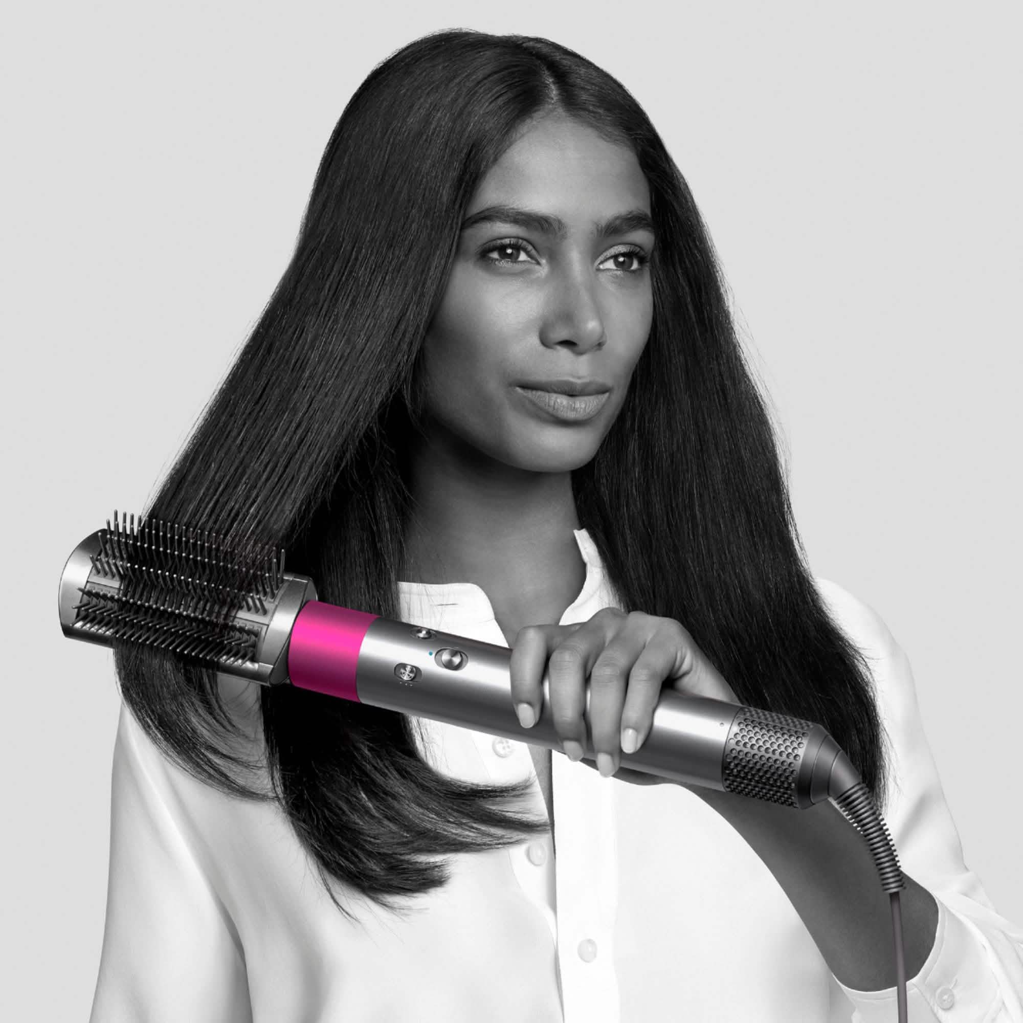 Woman using a Dyson Airwrap Complete Style For Multiple Hair Types And Styles to straighten her long hair