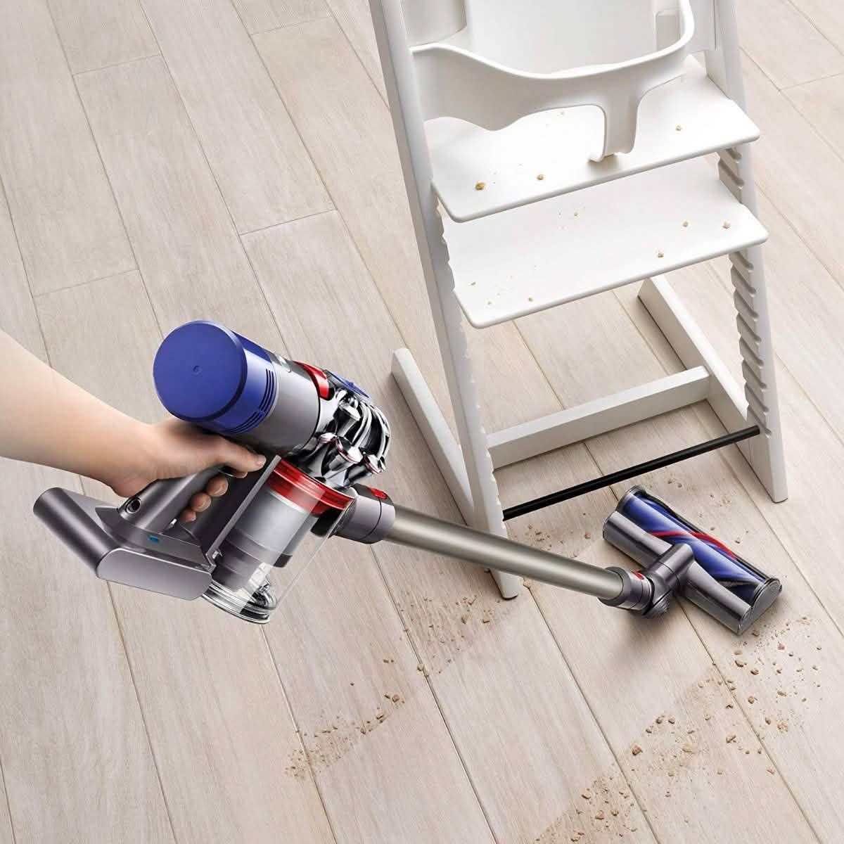 Person using the Dyson V8 Cordless Stick Vacuum Cleaner (Refurbished) to vacuum mess under a toddler high chair