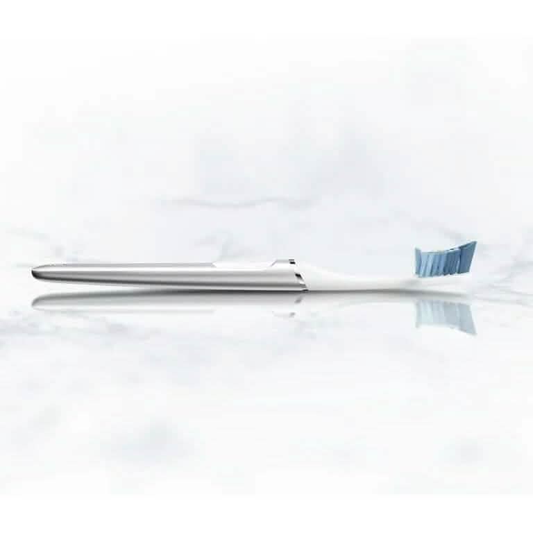 A white Oral-B Clic Manual Toothbrush lying on a white counter surface
