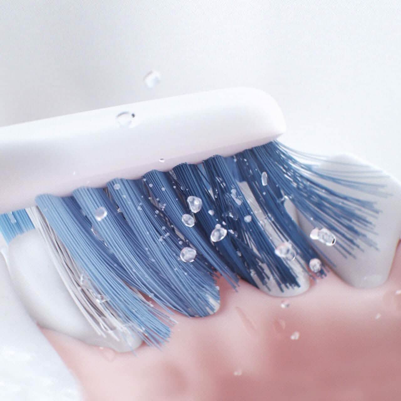 Closeup of the Oral-B Clic Manual Toothbrush brushing teeth against a white background