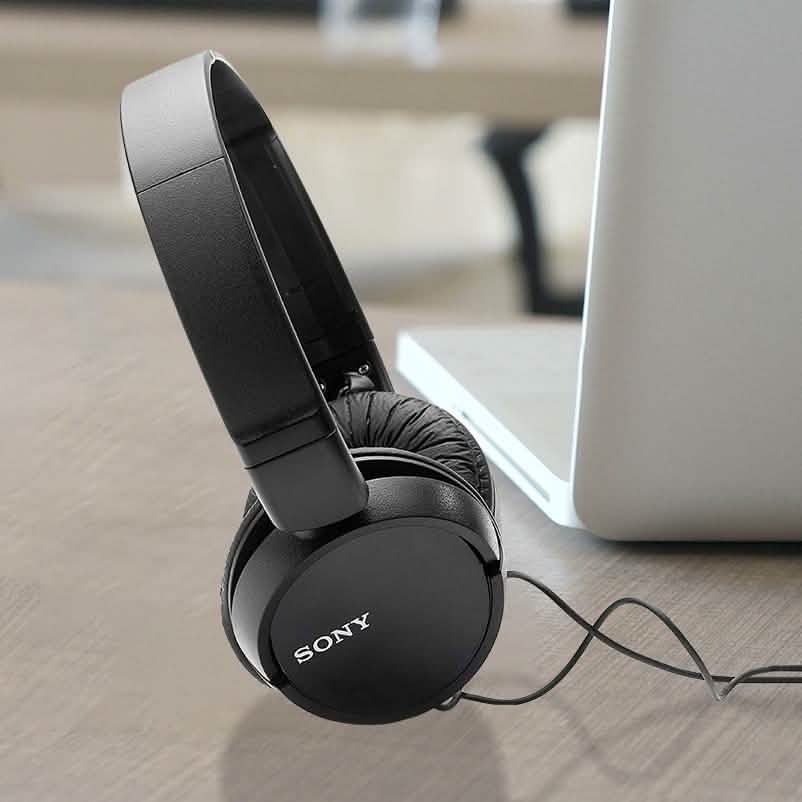 Closeup of black set of Sony MDRZX110 Stereo Headphones standing in front of a laptop computer