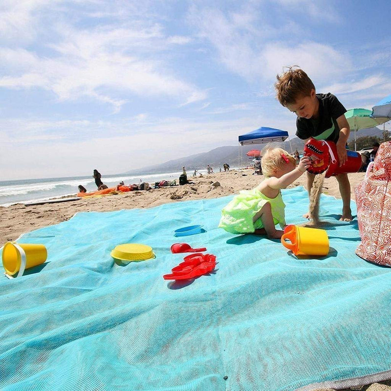 Two young children playing with sand toys on a blue Waterproof Sand Free Beach Mat in on a beach