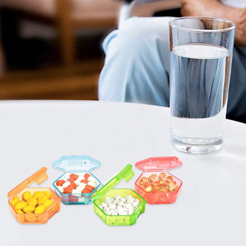Open pill boxes from 32-Piece Monthly Pill, Medicine And Vitamin Organizer With Tray shown on a table next to a glass of water