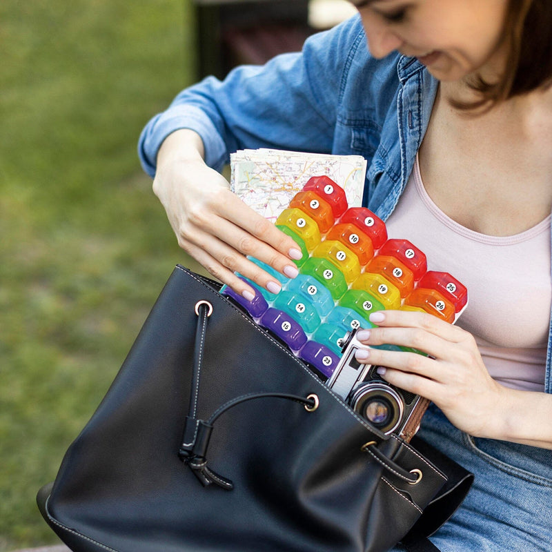 Woman putting a 32-Piece Monthly Pill, Medicine And Vitamin Organizer into her purse