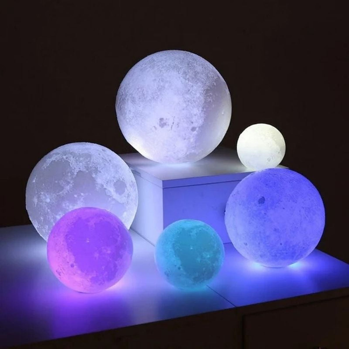 Several of the lamps lit in white, blue, purple and pink on a sideboard