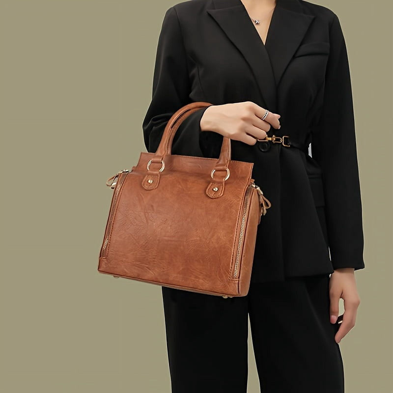 A woman in a black suit carrying the bag by its top handle