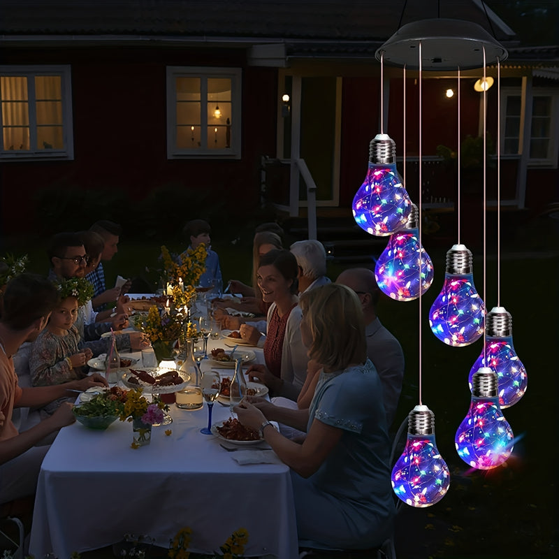 Hanging lit above an outdoor dinner table with guests seated below