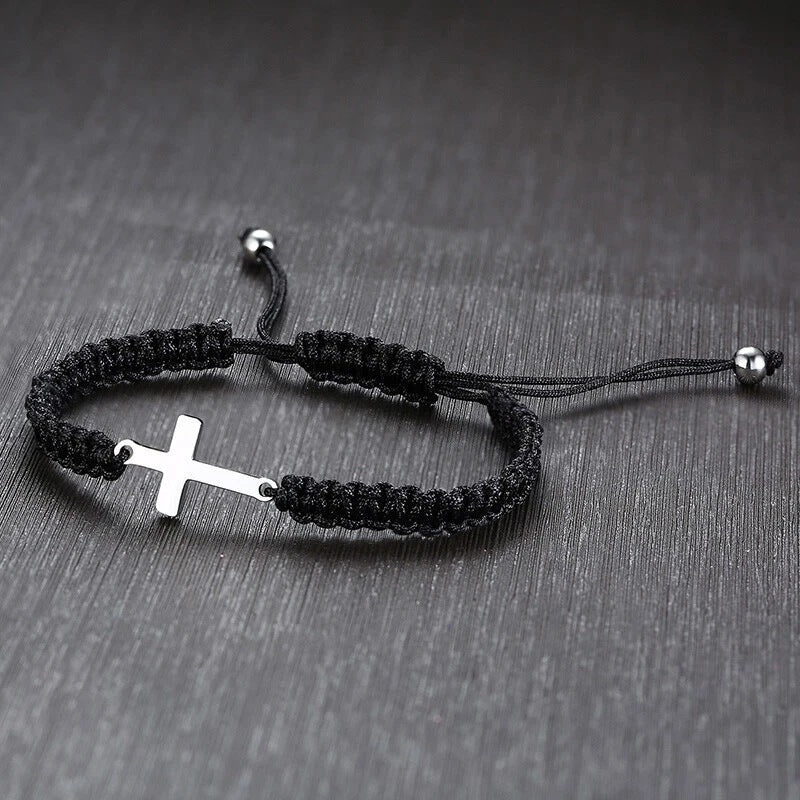 Cross charm braided bracelet on a dark wood surface