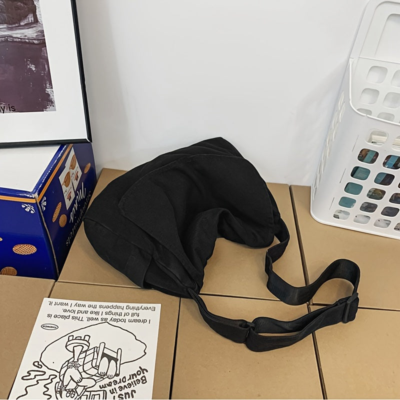 Black canvas bag laid flat with the strap coiled