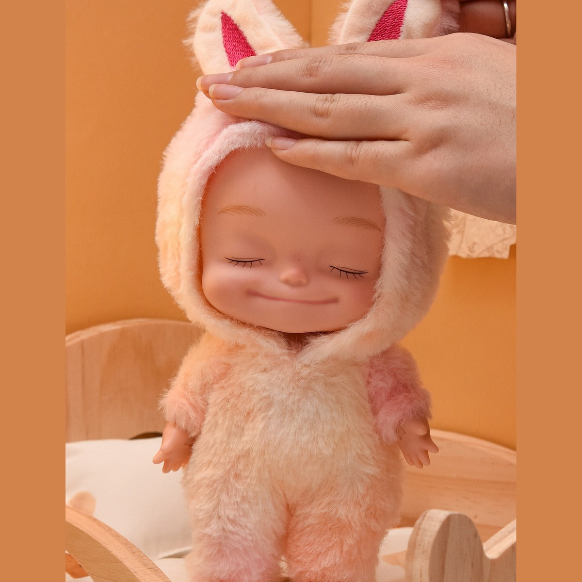 Pink plush onesie doll with eyes closed, standing