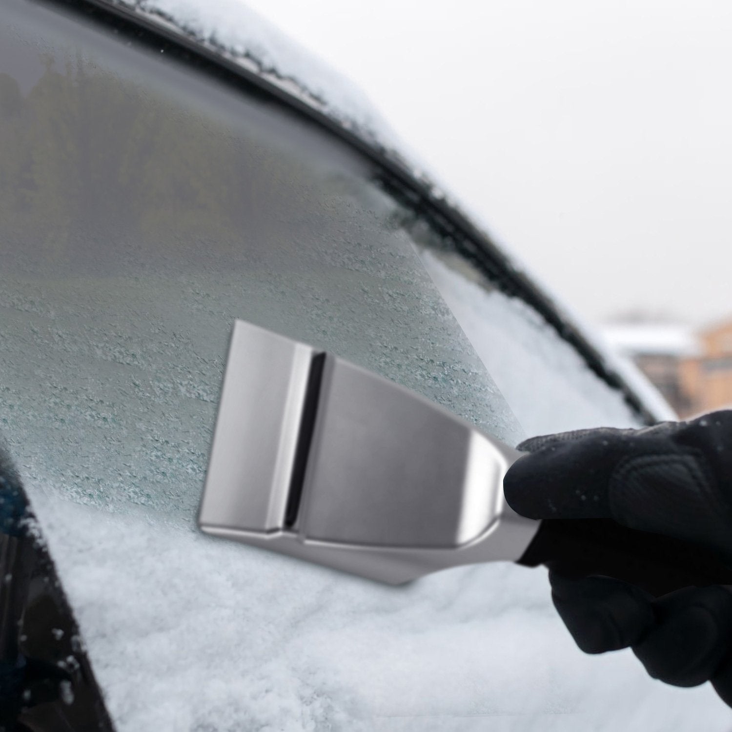 Gloved hand scraping ice off a windshield using a 12V Car Electric Heated Ice Snow Scraper in a winter day