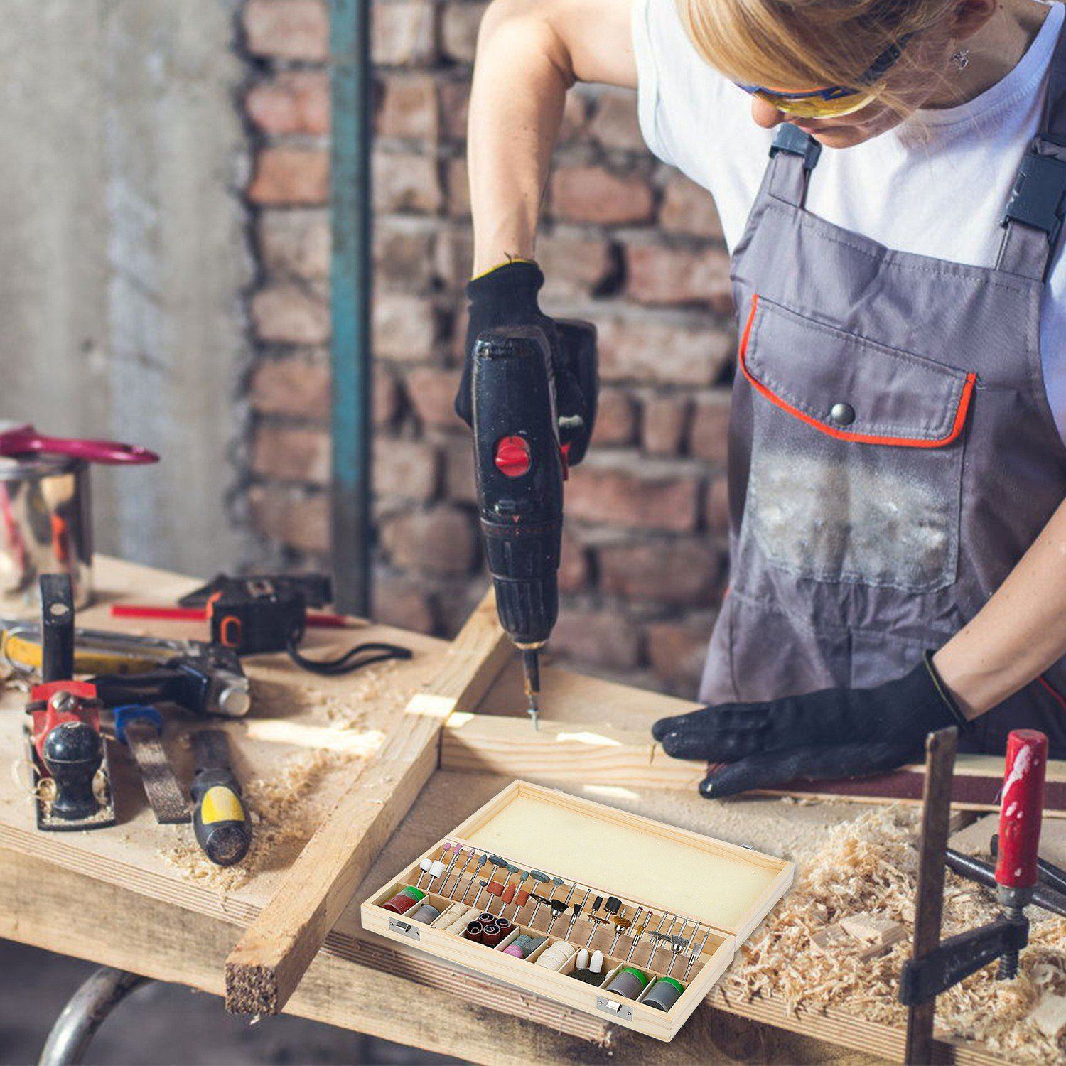 Woman wearing a set of goggles while using the Rotary Dremel tool from the 228-Piece Rotary Dremel Accessory Tool Kit to drive a screw into a piece of wood