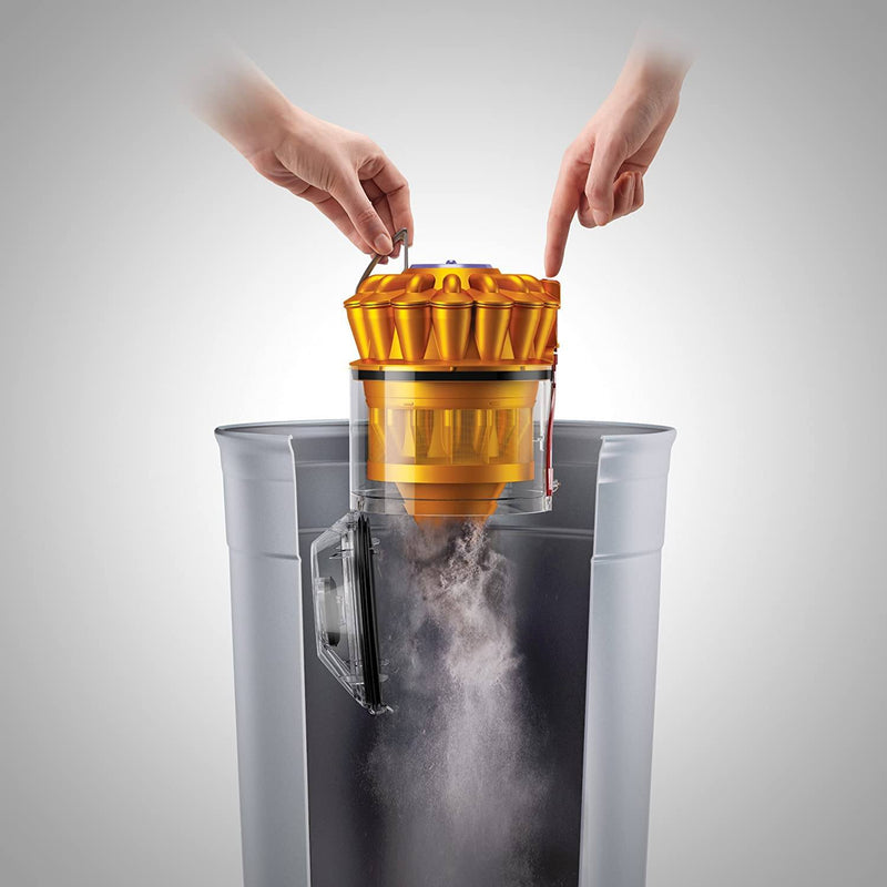 Pair of hands demonstrating the release of dirt collected by a Yellow Dyson DC39 Animal Canister Vacuum Cleaner (Refurbished) into a garbage bin