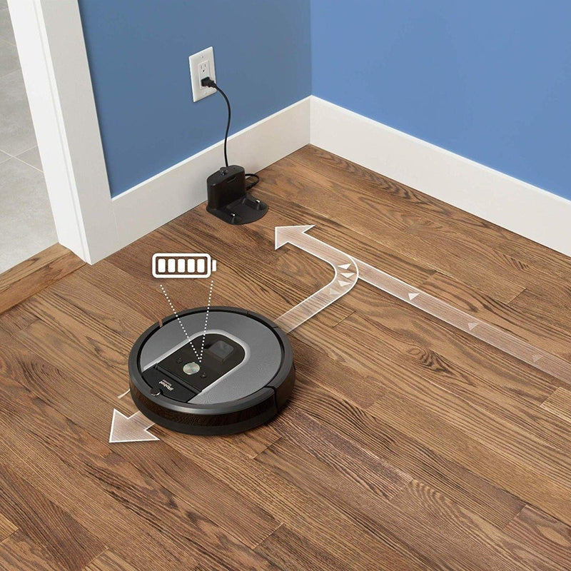 iRobot Roomba 960 Robot Vacuum shown in action with rechargable spare battery plugged into a wall socket behind