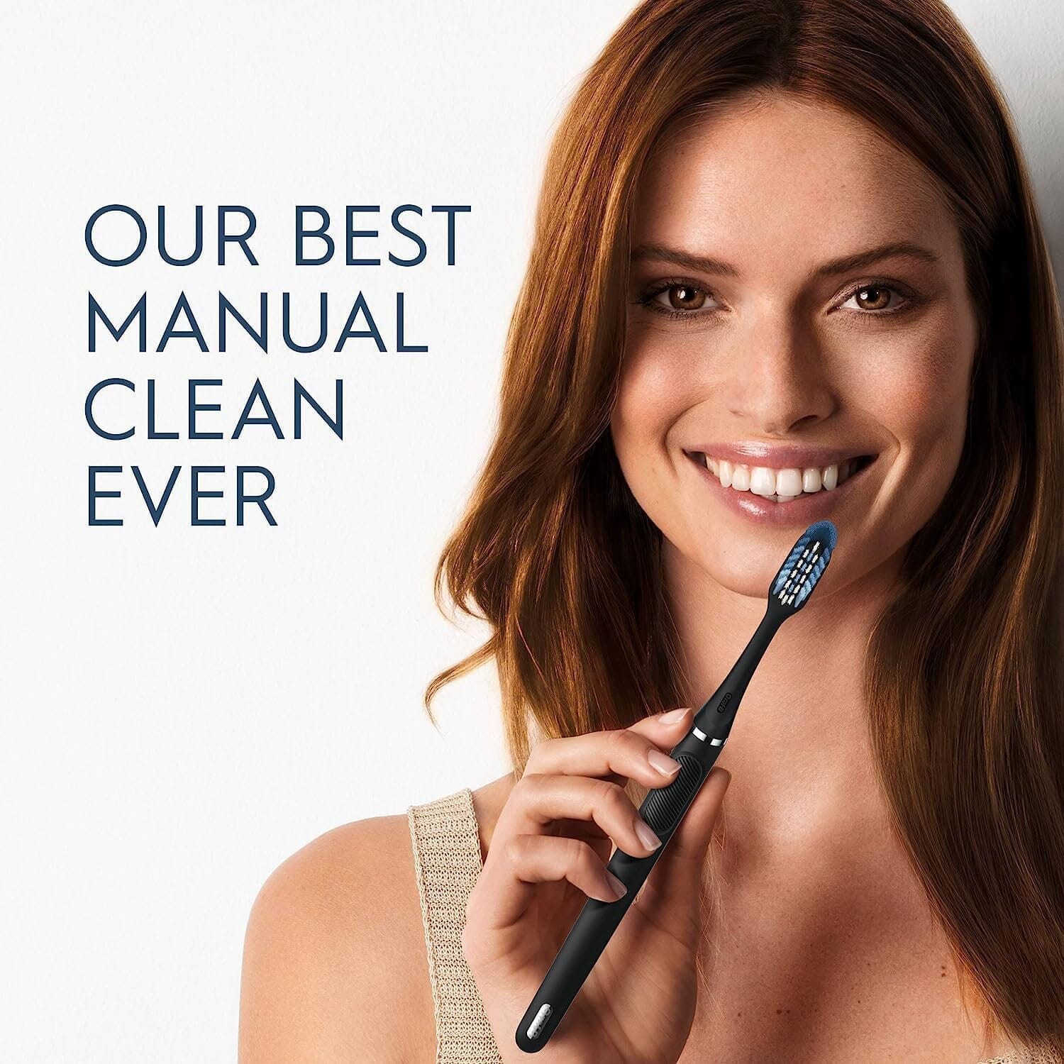 Smiling woman holding an Oral-B Clic Manual Toothbrush with her hand with a sign that says "Our best manual clean ever"